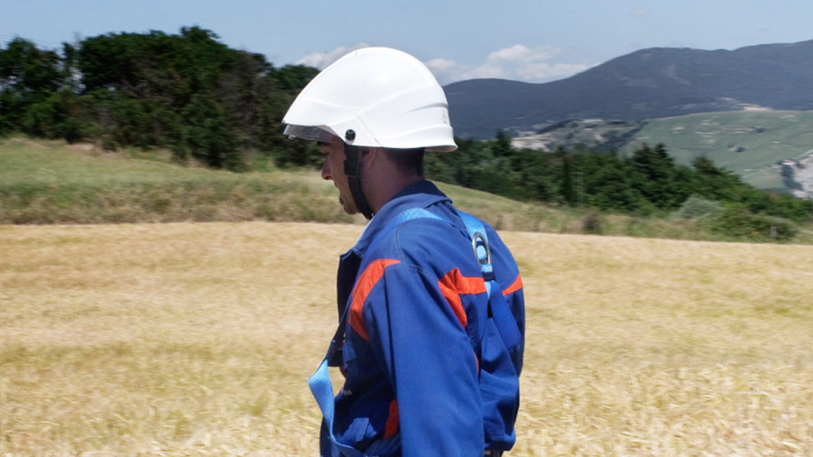 Foto di un tecnico di e-distribuzione che cammina in campagna