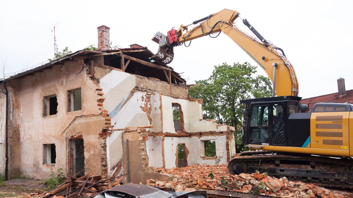 foto di un escavatore che demolisce un edificio