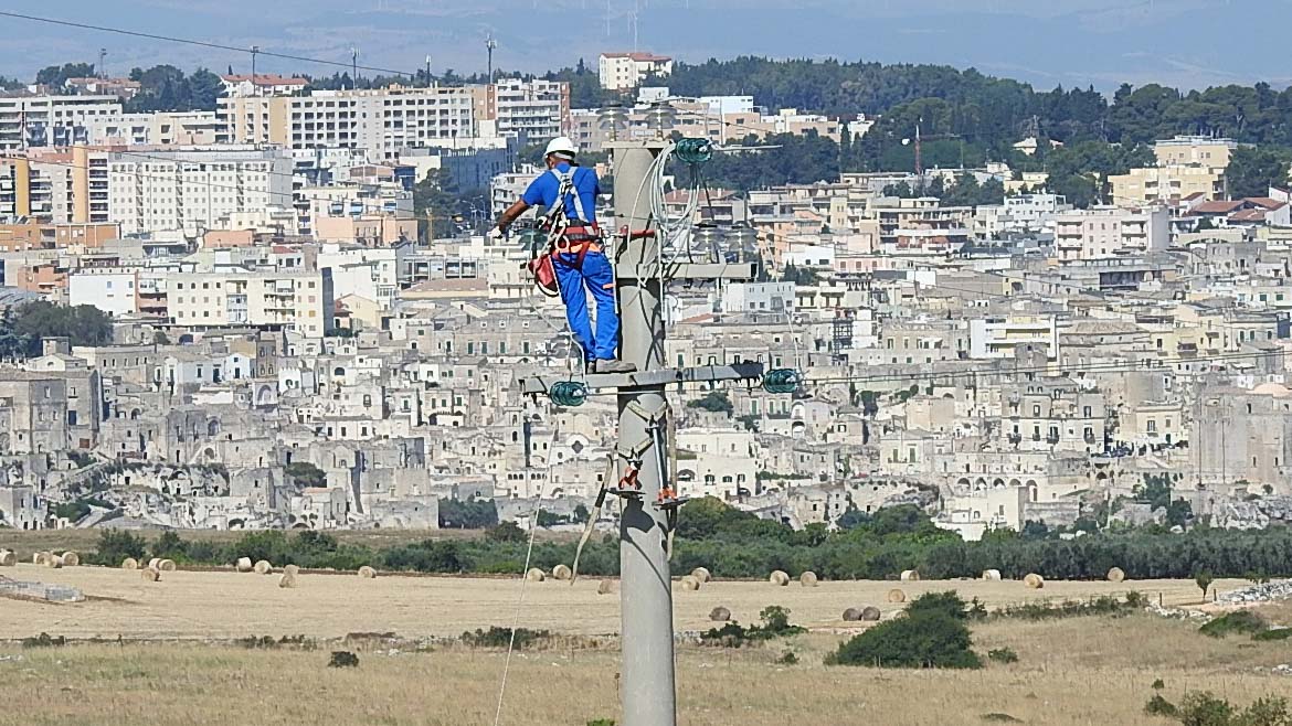 Foto di un tecnico di E-distribuzione a lavoro su un traliccio di Matera