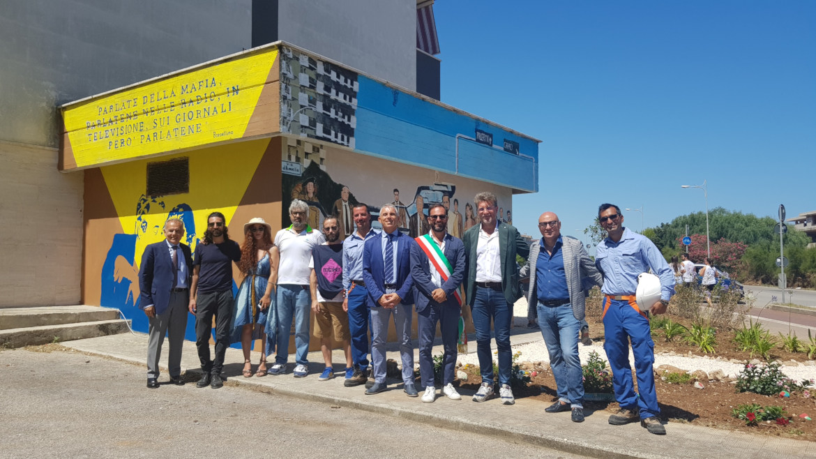 un gruppo di persone davanti alla cabina di mola di bari con la sua street art